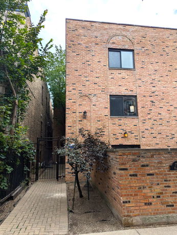 Brick exterior of a multi-story building with windows and a gated pathway.