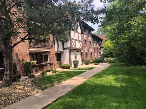 Front view of a multi-story residential building with brick and timber accents.