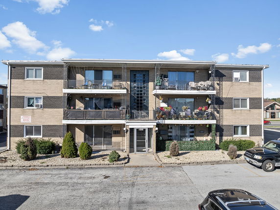 Front view of a three-story apartment building with balconies.