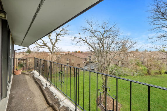 Balcony view towards residential buildings with a lawn and trees.