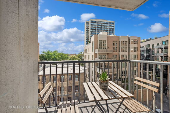 View from a balcony showing nearby buildings and a clear sky.