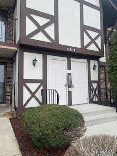 Front view of a two-story building with decorative cross timber elements and double doors.