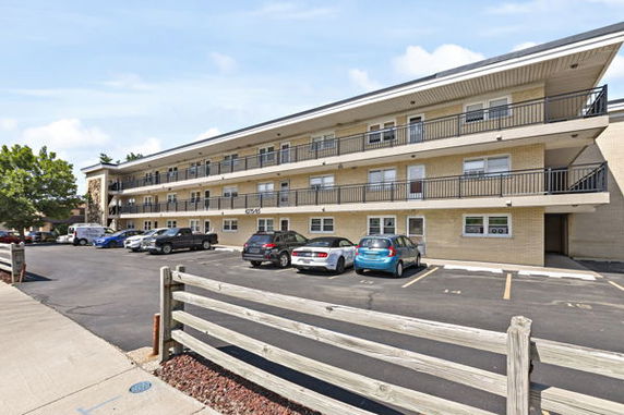 Front view of a three-story residential building with parking area.