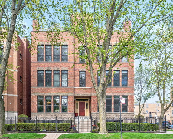 Front view of a multi-story brick building with large windows.