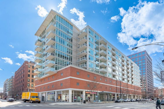 Front view of a multi-story commercial and residential building with glass balconies.