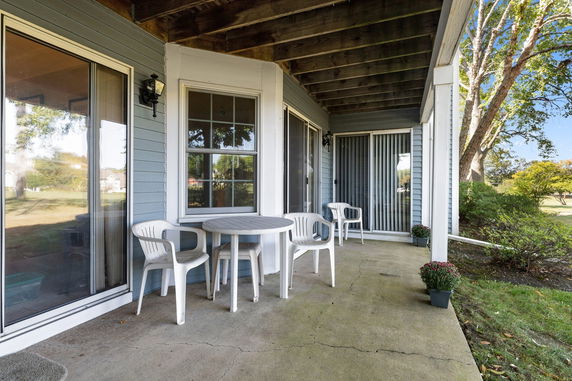 Front view of a house with a covered patio and chairs.