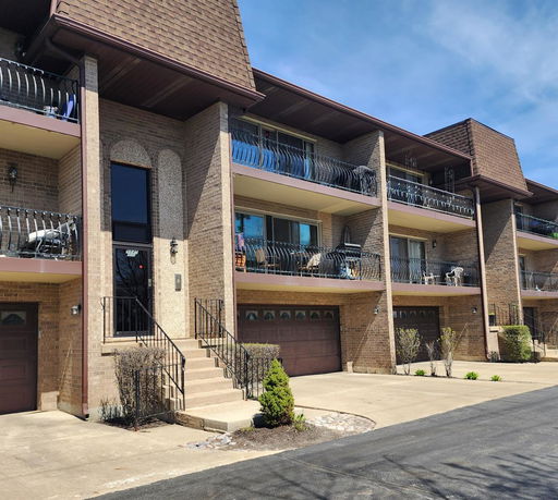 Front view of a multi-story residential building with balconies and garages.