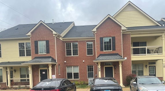 Front view of a two-story house with a brick facade and multiple entrances.