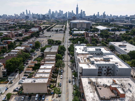 Aerial view of a cityscape with streets, buildings, and a distant skyline.
