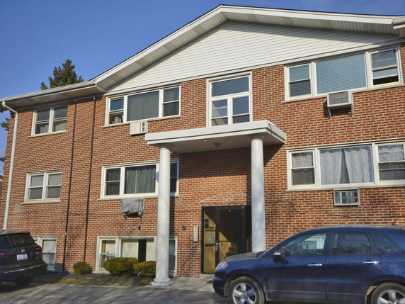 Front view of a two-story brick apartment building with multiple windows and a central entrance.