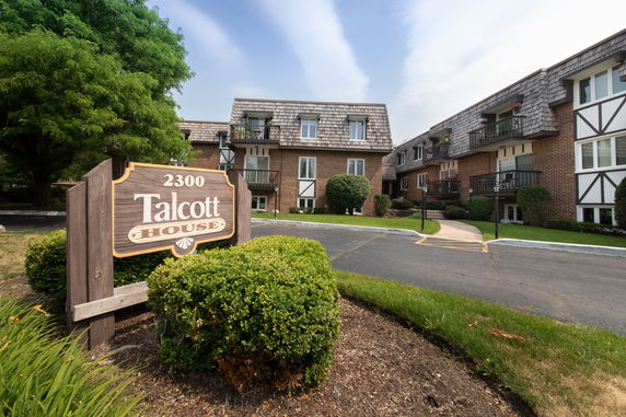 Front view of a multi-story brick building with a wooden shingle roof and balconies.