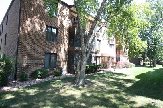 Front view of a multi-story brick apartment building with balconies.