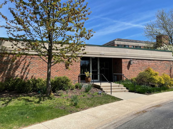 Front view of a single-story brick building with entrance steps and a railing.