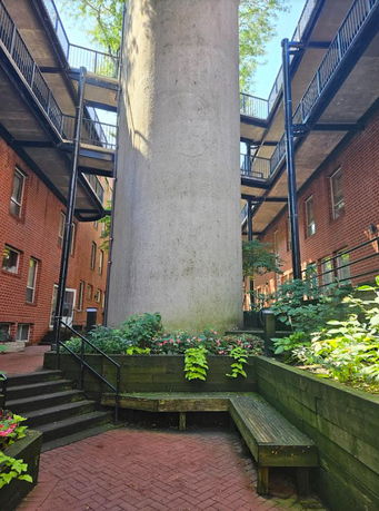 Outdoor view of a courtyard with red brick buildings and an overhead walkway.