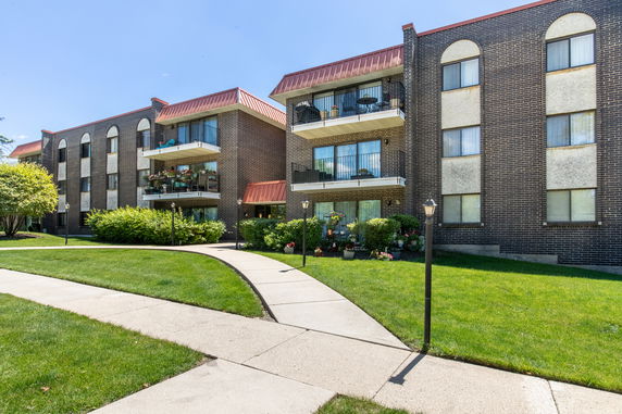 Front view of a multi-story brick apartment building with balconies.