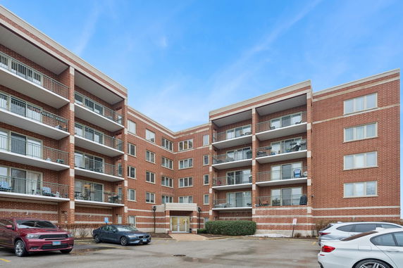 Front view of a multi-story brick apartment building with balconies.