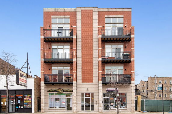 Front view of a multi-story building with commercial spaces on the ground floor.
