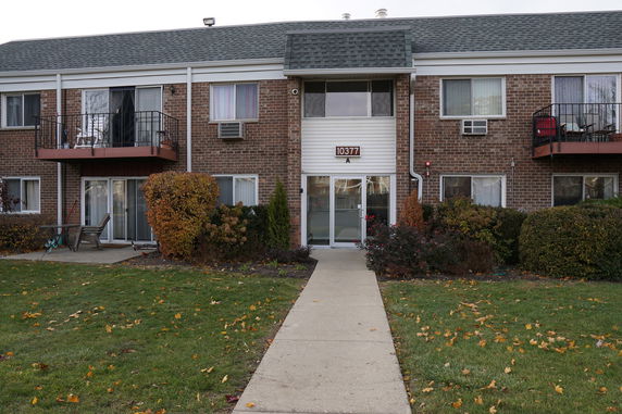 Front view of a two-story brick apartment building with balconies and a central entrance.