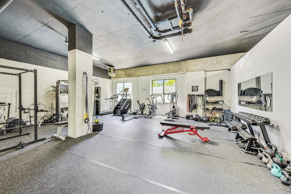 Indoor gym area equipped with exercise machines and weights.