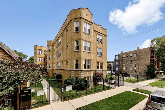 Front view of a multi-story brick building with a gated entrance.