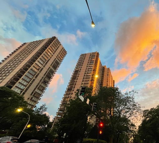 Street-level view of tall residential buildings against a colorful sky.