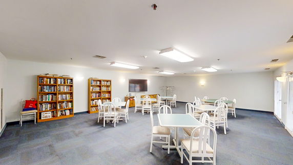 Indoor room with tables, chairs, and bookshelves.