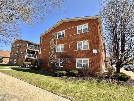 Front view of a multi-story apartment building with a brick facade.