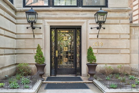 Front entrance of a building with a decorative metal door and lanterns on either side.