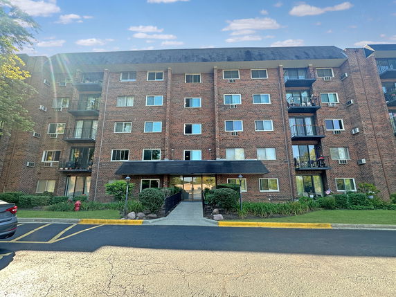 Front view of a multi-story apartment building with brick facade and balconies.
