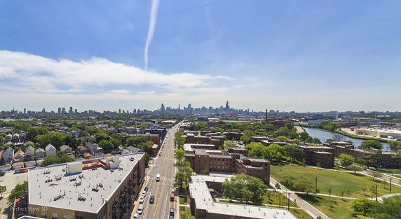 Aerial panoramic view of a cityscape with buildings and streets, showing a distant city skyline.