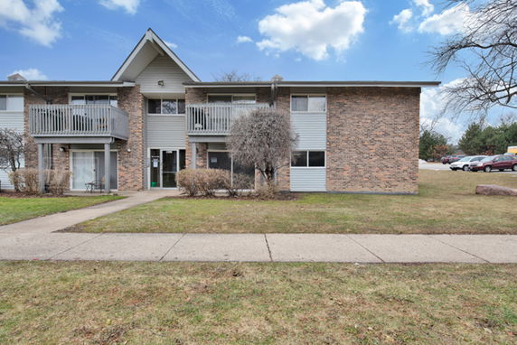 Front view of a two-story residential building with brick and siding exterior and two balconies.