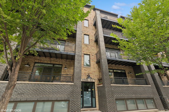 Front view of a multi-story brick building with balconies and large windows.