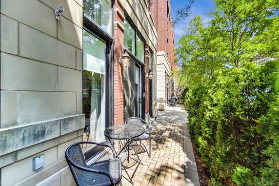 Exterior view of a brick and stone building with large windows and a small outdoor seating area.
