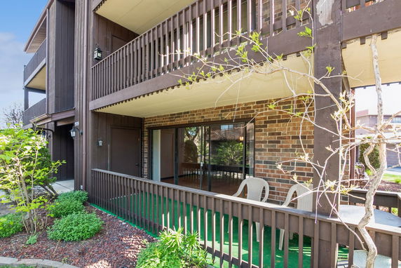 Front view of a multi-story building with wooden balconies and brick walls.