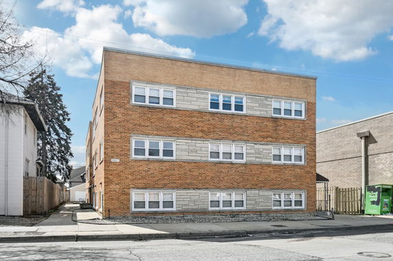 Front view of a three-story brick apartment building with multiple windows.