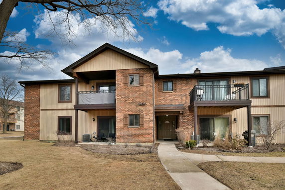 Front view of a two-story brick and wood house with balconies.
