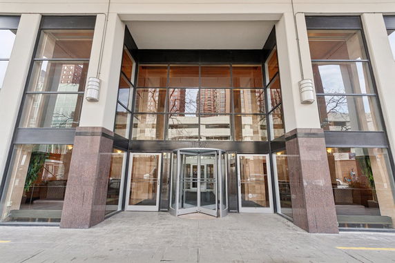 Front view of a multi-story building entrance with glass facade and revolving door.