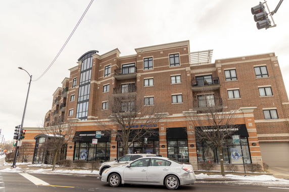 Front view of a multi-story brick building with balconies and large windows.