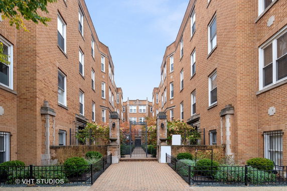Front view of a brick residential building with multiple stories and a gated entrance.