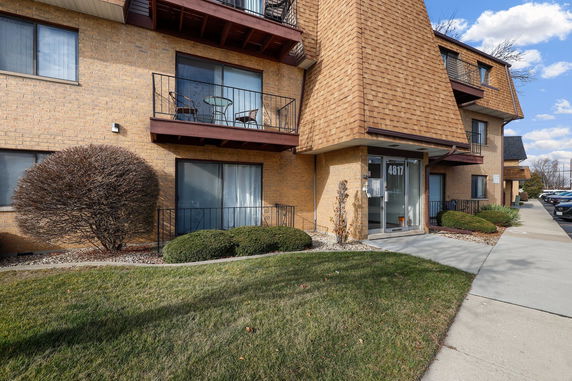 Front view of a multi-story building with balconies and a glass entrance door.