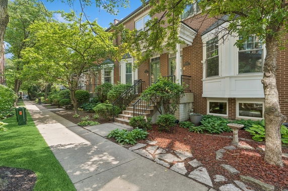 Front view of a multi-story brick house with stairs leading to the entrance.