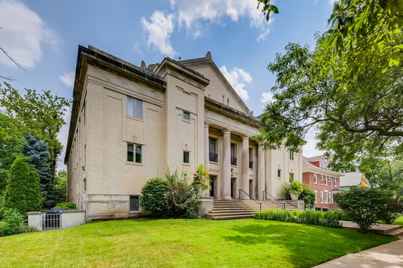 Front view of a large building with columns and a sloped roof.