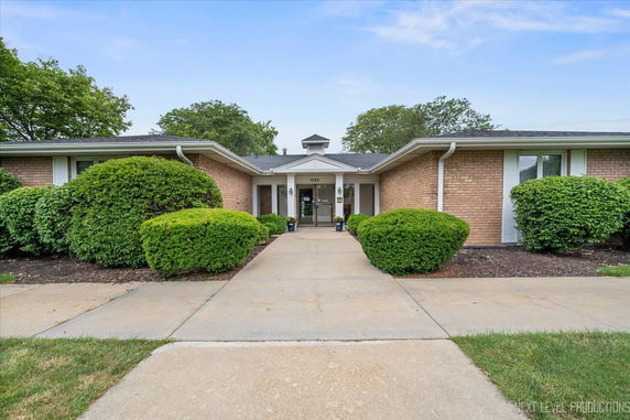 Front view of a single-story building with brick exterior and landscaped bushes.