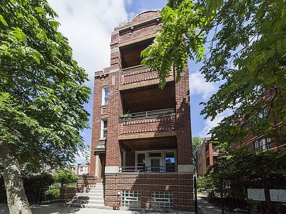 Front view of a three-story brick building with balconies.