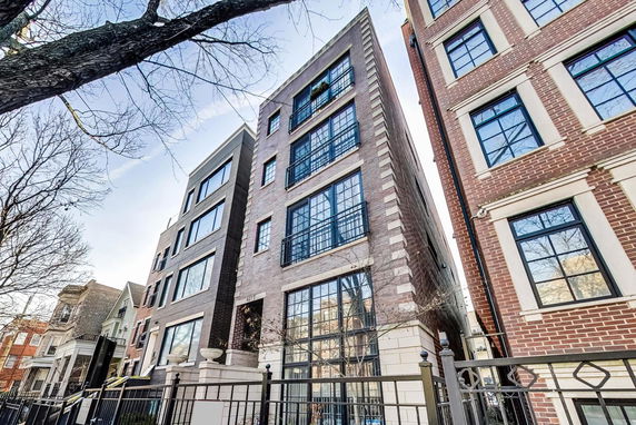 Front view of a multi-story residential building with large windows and brick facade.