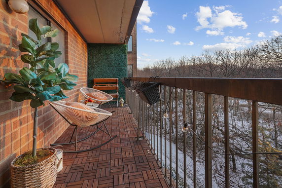 Balcony view with outdoor seating overlooking a snow-covered landscape and trees.