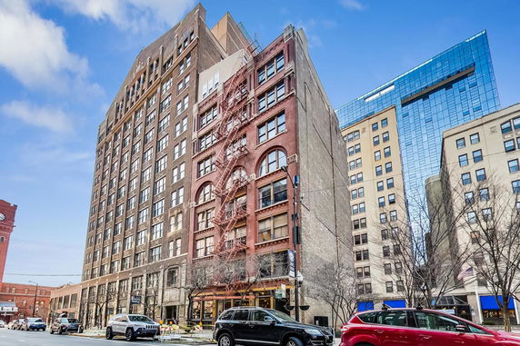 Front view of a multi-story urban building with large windows and a fire escape.