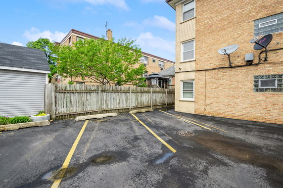 Outdoor parking area with marked parking spots beside a brick building.