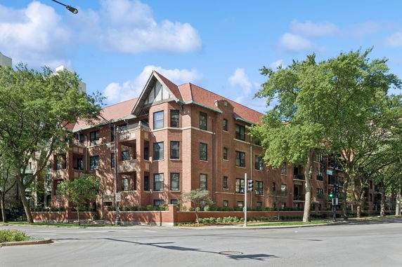 Front view of a multi-story brick building with a pitched roof.