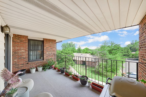 View from a balcony overlooking a neighborhood with trees and buildings.